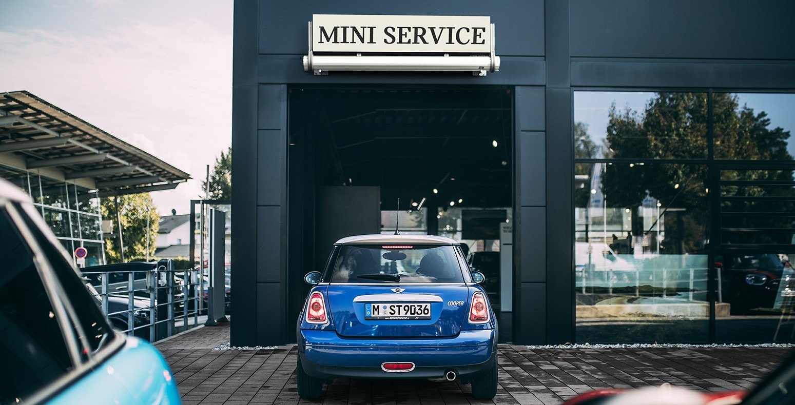 Rear view of a MINI Hatch in Electric Blue Metallic entering a MINI Service center.